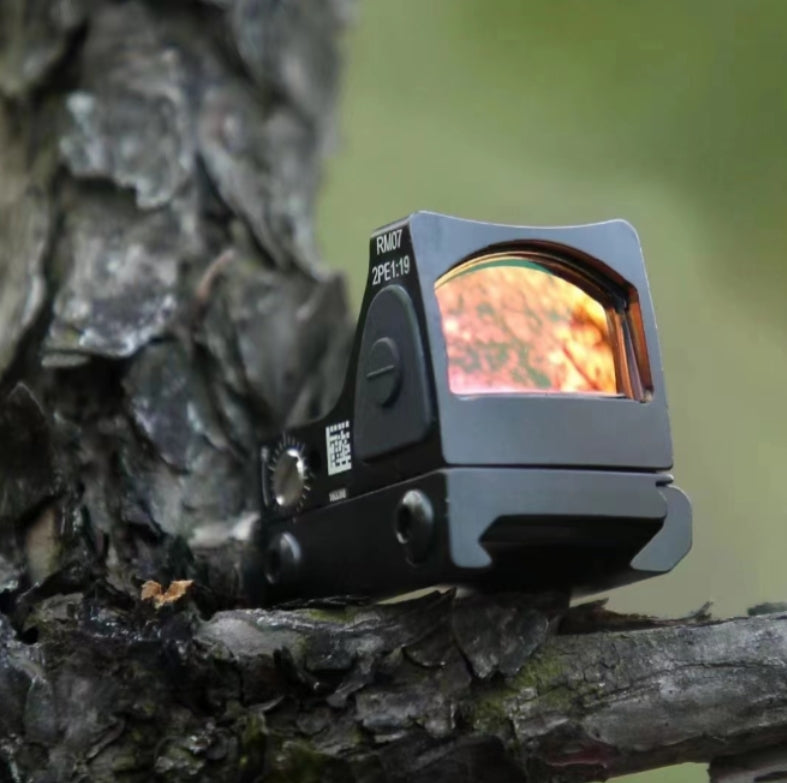 Trijicon RM07 red dot sight mounted on tree for outdoor durability showcase